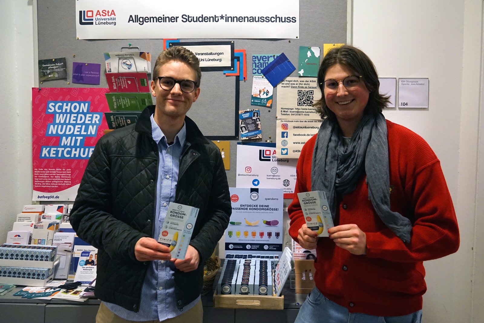 Spondoms'tan Luis (solda), Lüneburg Leuphana Üniversitesi AStA'dan Max (sağda) ile birlikte ücretsiz prezervatif dağıtıcısını açıyor